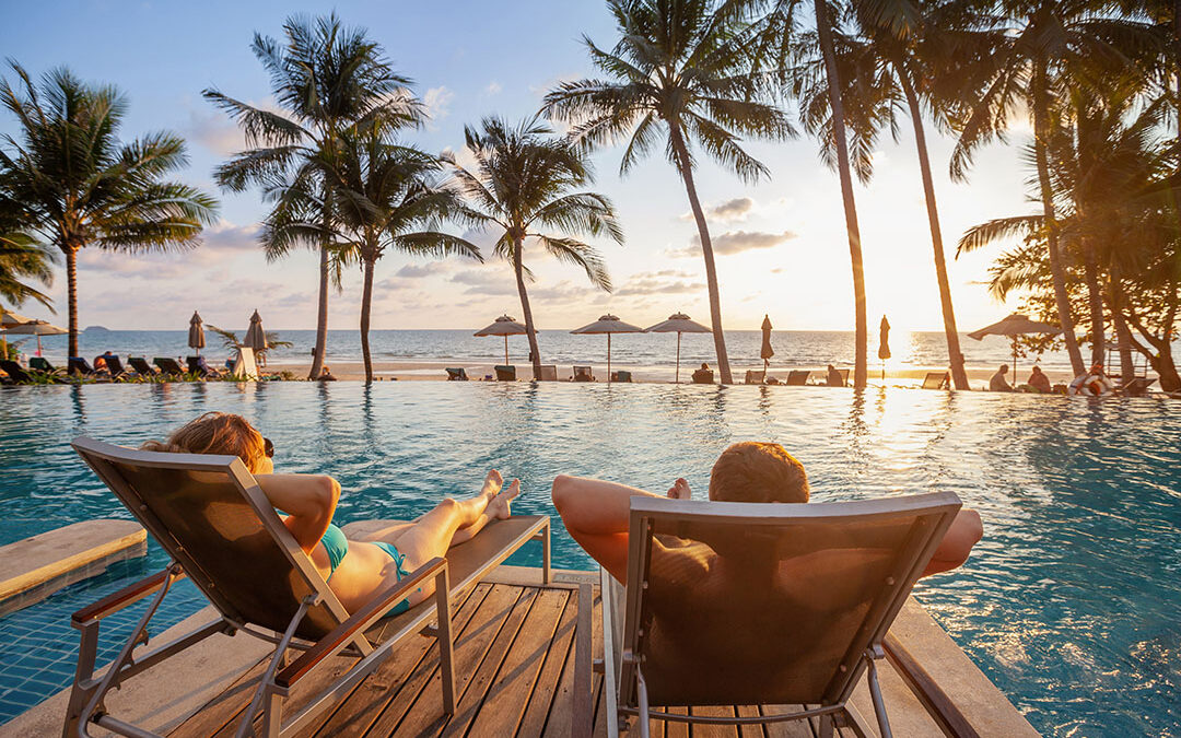A couple relaxing poolside at a luxurious tropical resort during sunset, embodying the dream vacation experience that transcends the mere purchase of a plane ticket.